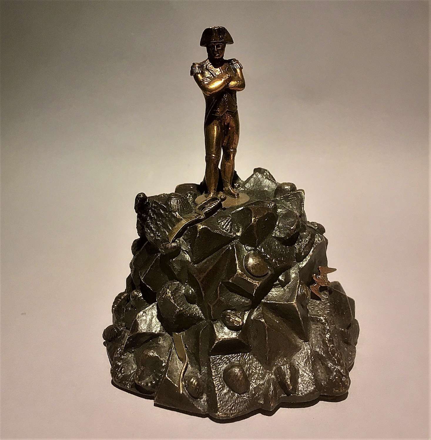 A small bronze sculpture of Napoleon standing on a rocky outcrop